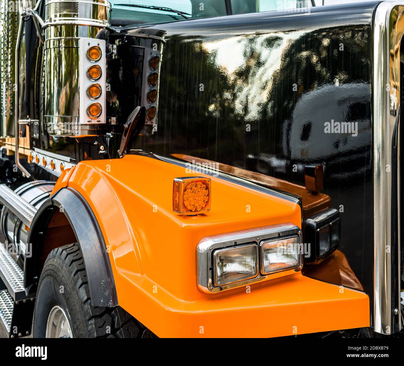 Front part of commercial freight transportation stylish black and orange  big rig semi truck tractor with chrome accessories and glass headlight and  re Stock Photo - Alamy