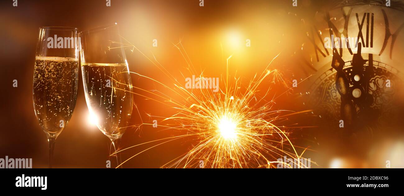 Champagne for solemn good wishes. Luminous golden background with sparkler and clock time for special occasions. Stock Photo