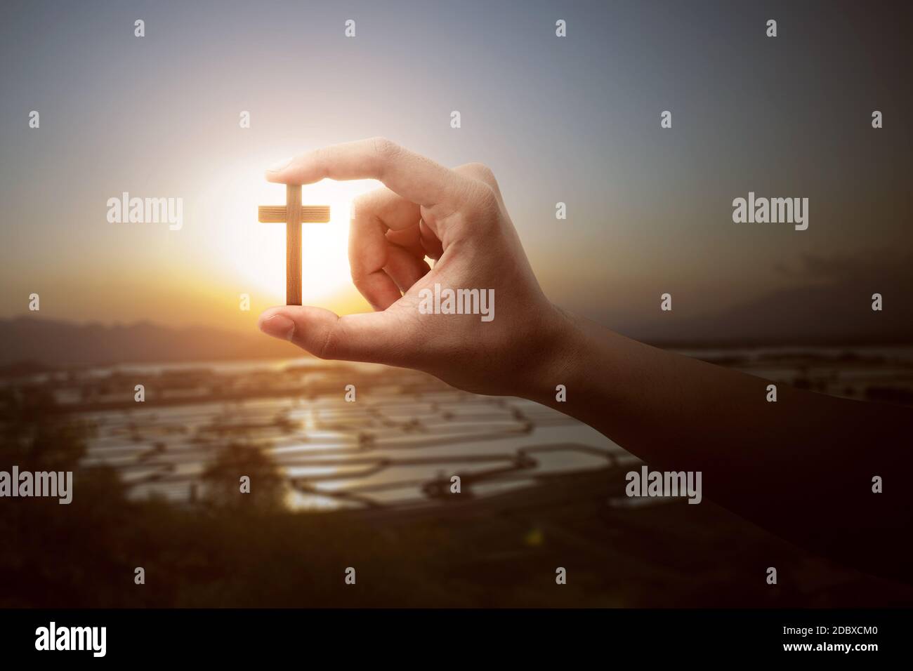Human hand holding Christian cross with a sunset sky background Stock ...