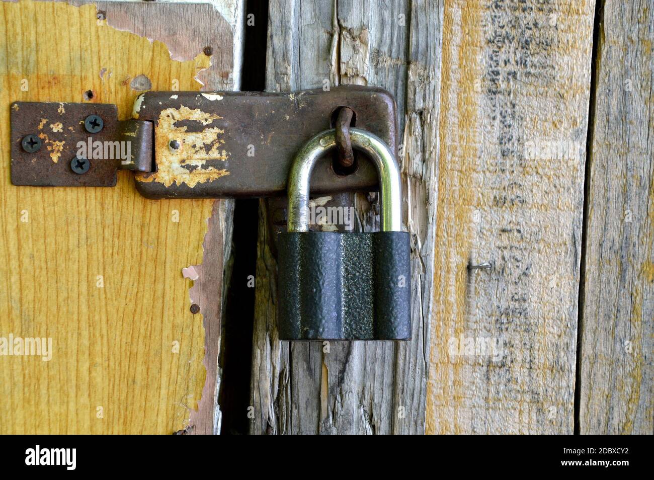Old padlock hanging on a wooden shabby door Stock Photo