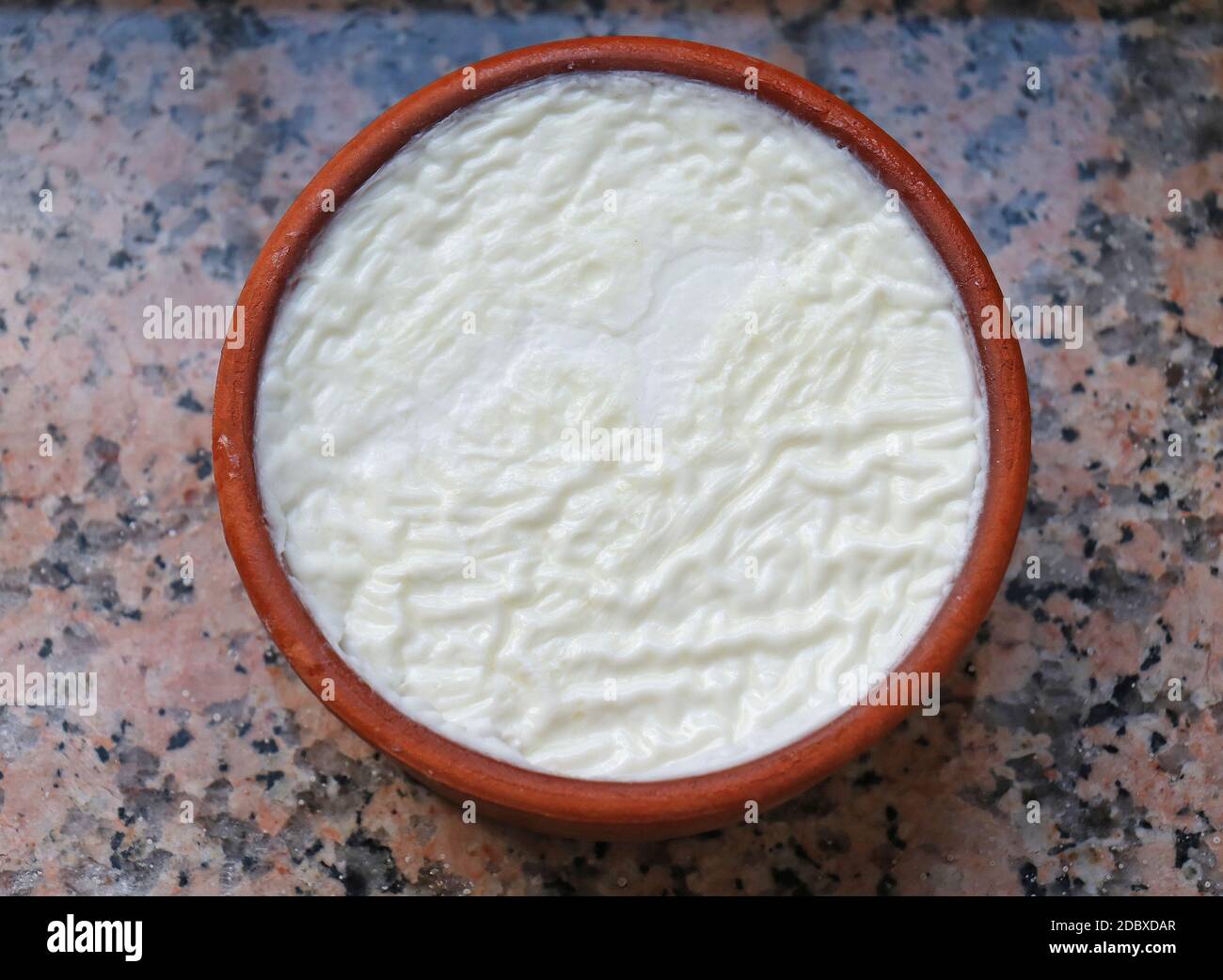 Traditional Greek style yogurt in ceramic jar on marble desk Stock