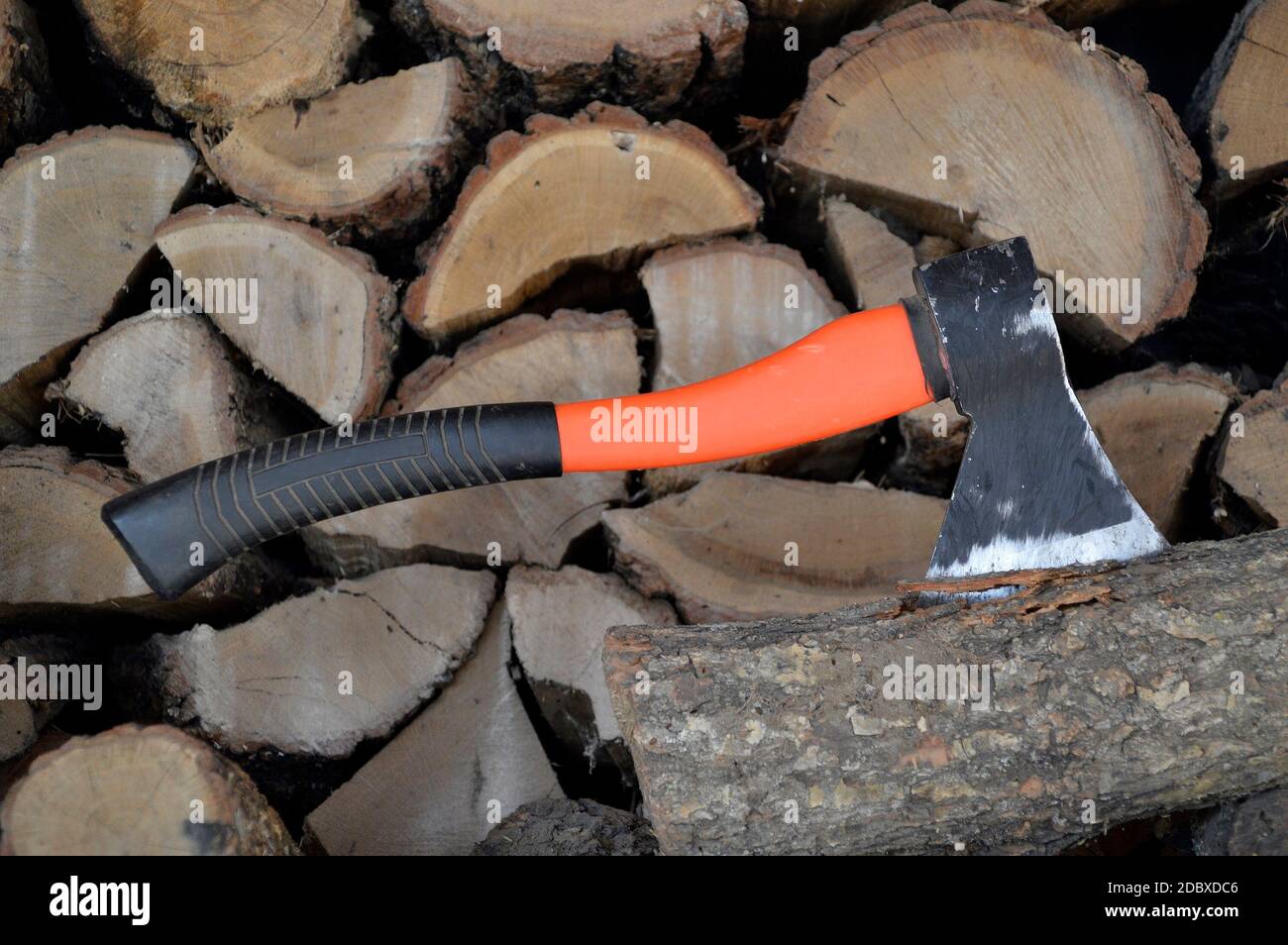 Ax stuck in a log against the background of lumber Stock Photo