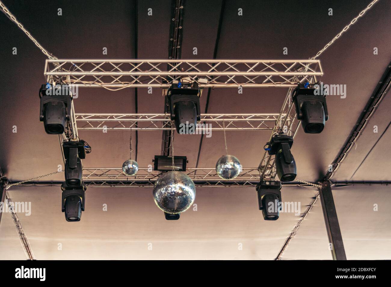Several disco balls and strobe lights hang from the ceiling of the nightclub Stock Photo