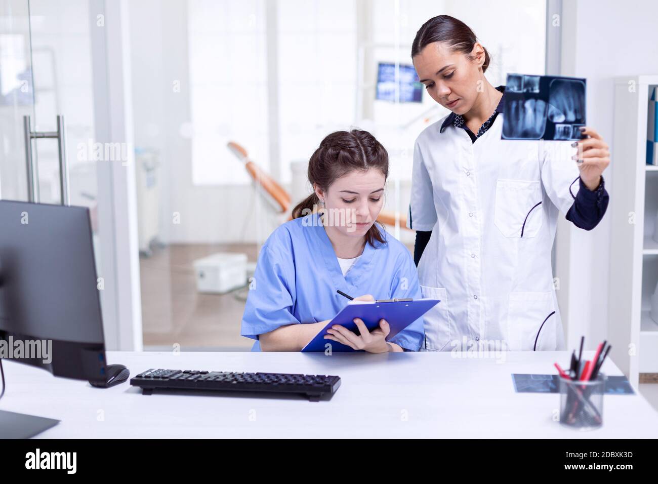 Dentist nurse taking notes about teeth hygine while doctor is holding x ...