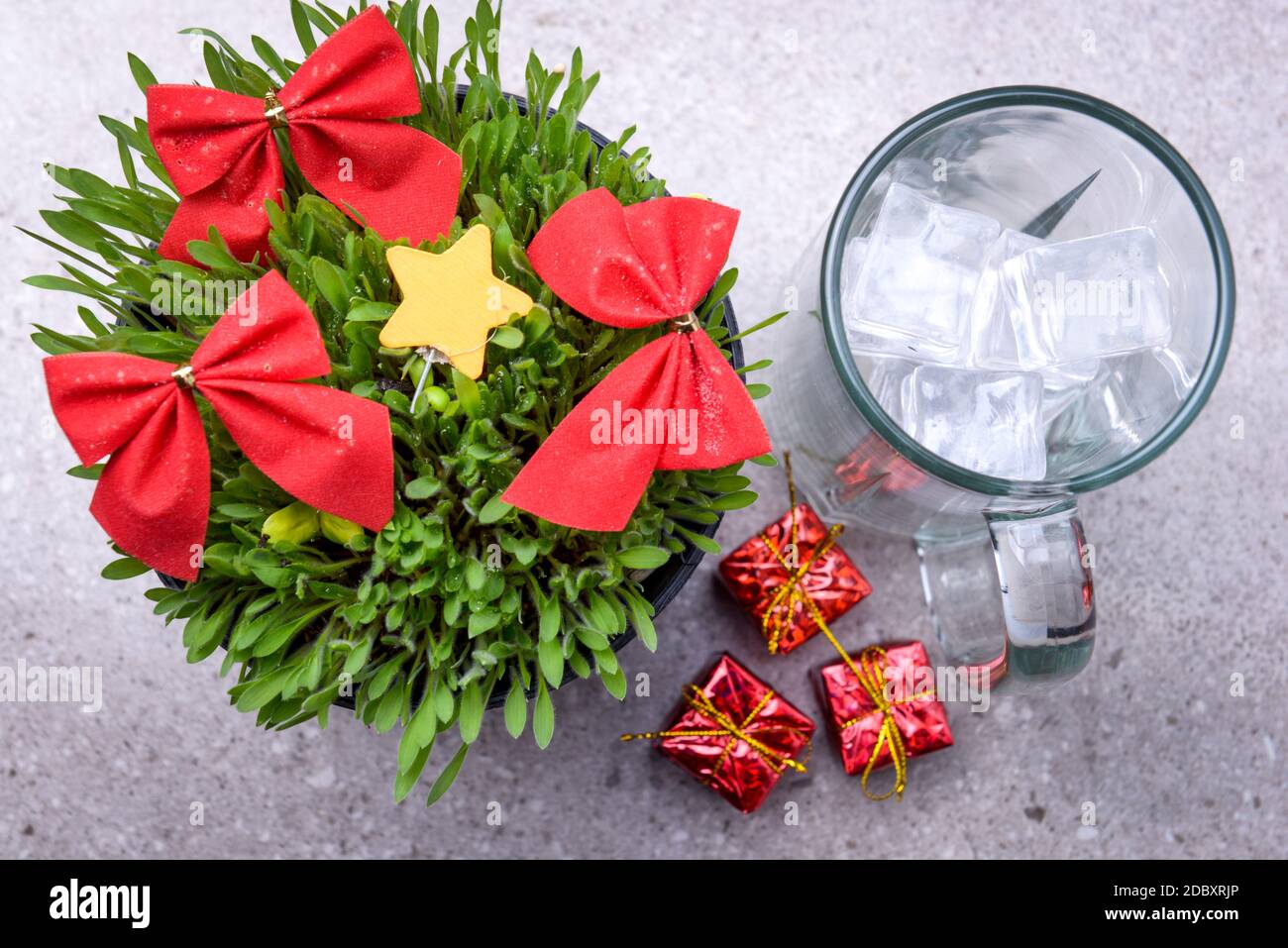 Close up view of millet grass plant with Christmas ornament in the pot and glasses with an ice cube on the desk Stock Photo