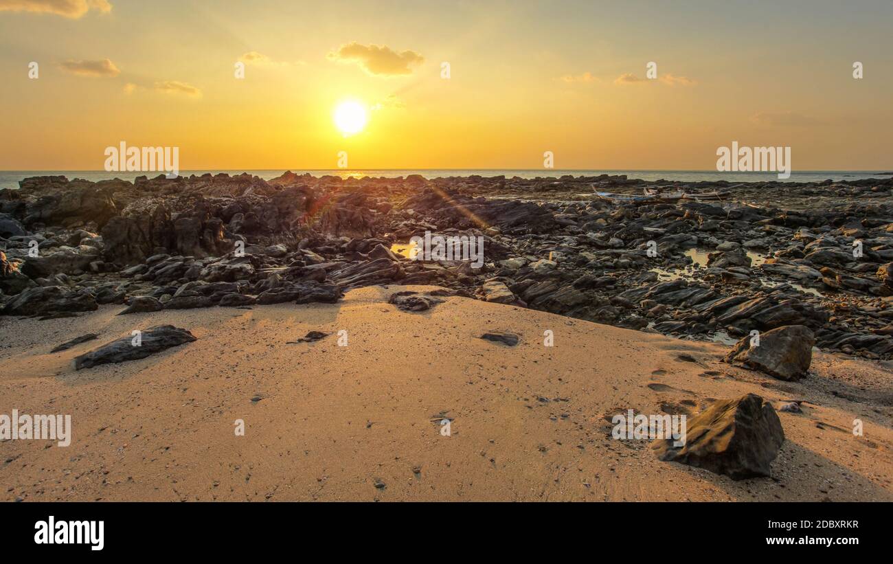 Rocks and sandy beach uncovered in low tide with boats on dry land in  background during evening sunset light. Koh Lanta, Thailand Stock Photo -  Alamy