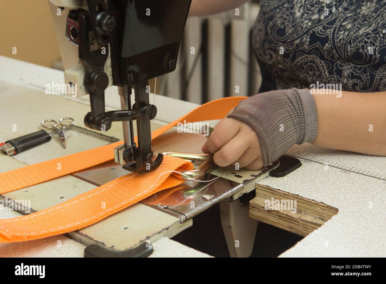 Industrial sewing machine sews a webbing sling. Manufacture of textile slings and tie straps
