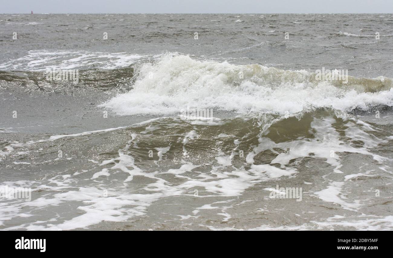 Waves with white crests inundate the sandy beach Stock Photo
