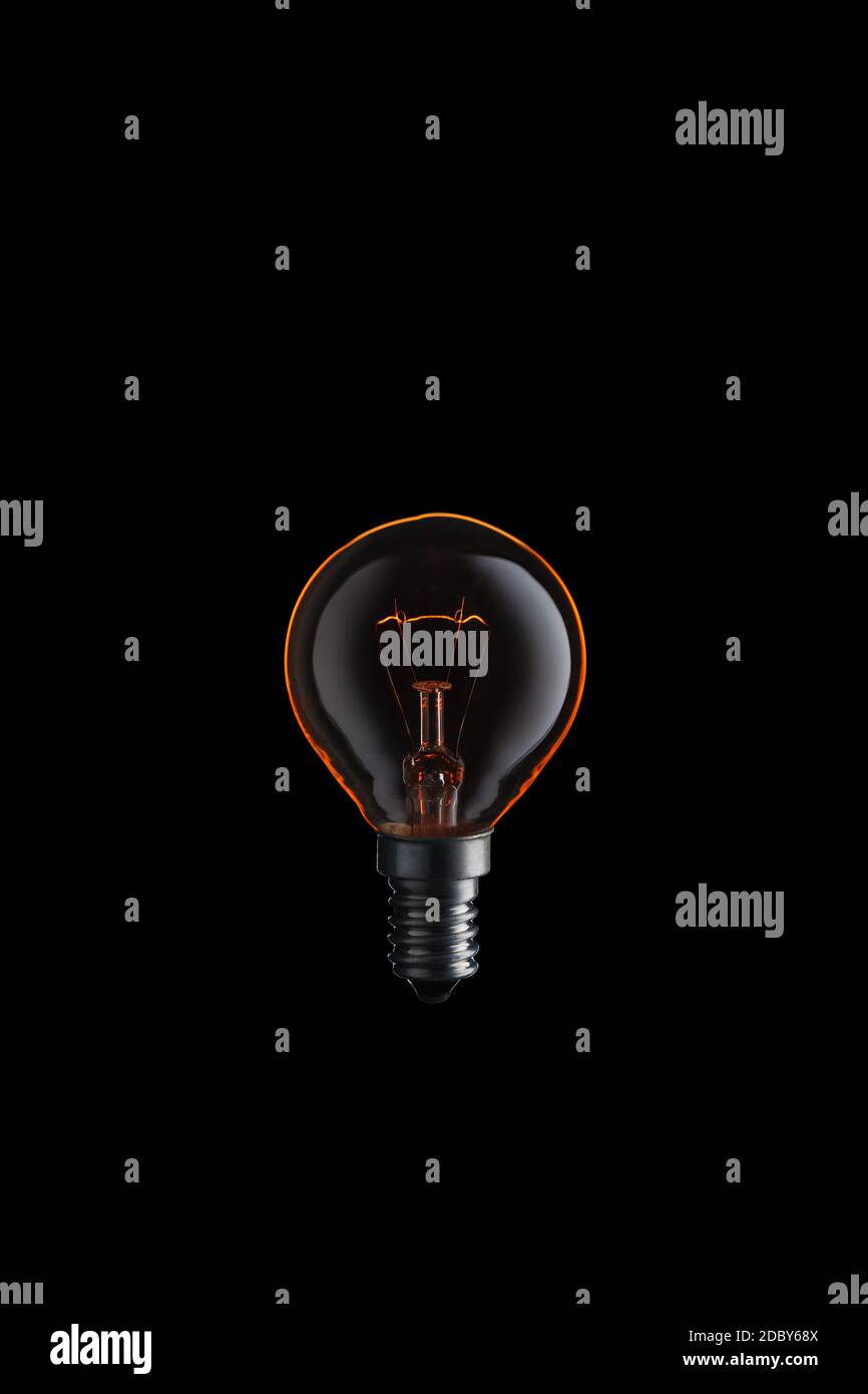 Burning Light bulb on black background. Stock Photo