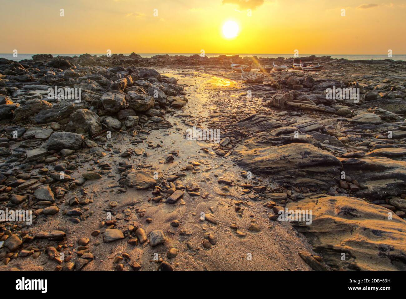 Rocks and beach uncovered in low tide with boats on dry land in background  during evening sunset back light. Koh Lanta, Thailand Stock Photo - Alamy