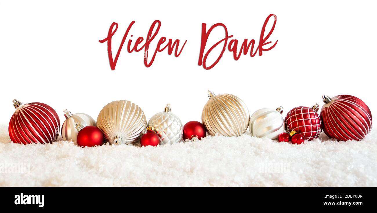 German Calligraphy Vielen Dank Means Thank You On Isolated White Backgroud. Red And White Festive Christmas Ball Ornament On Snow. Stock Photo