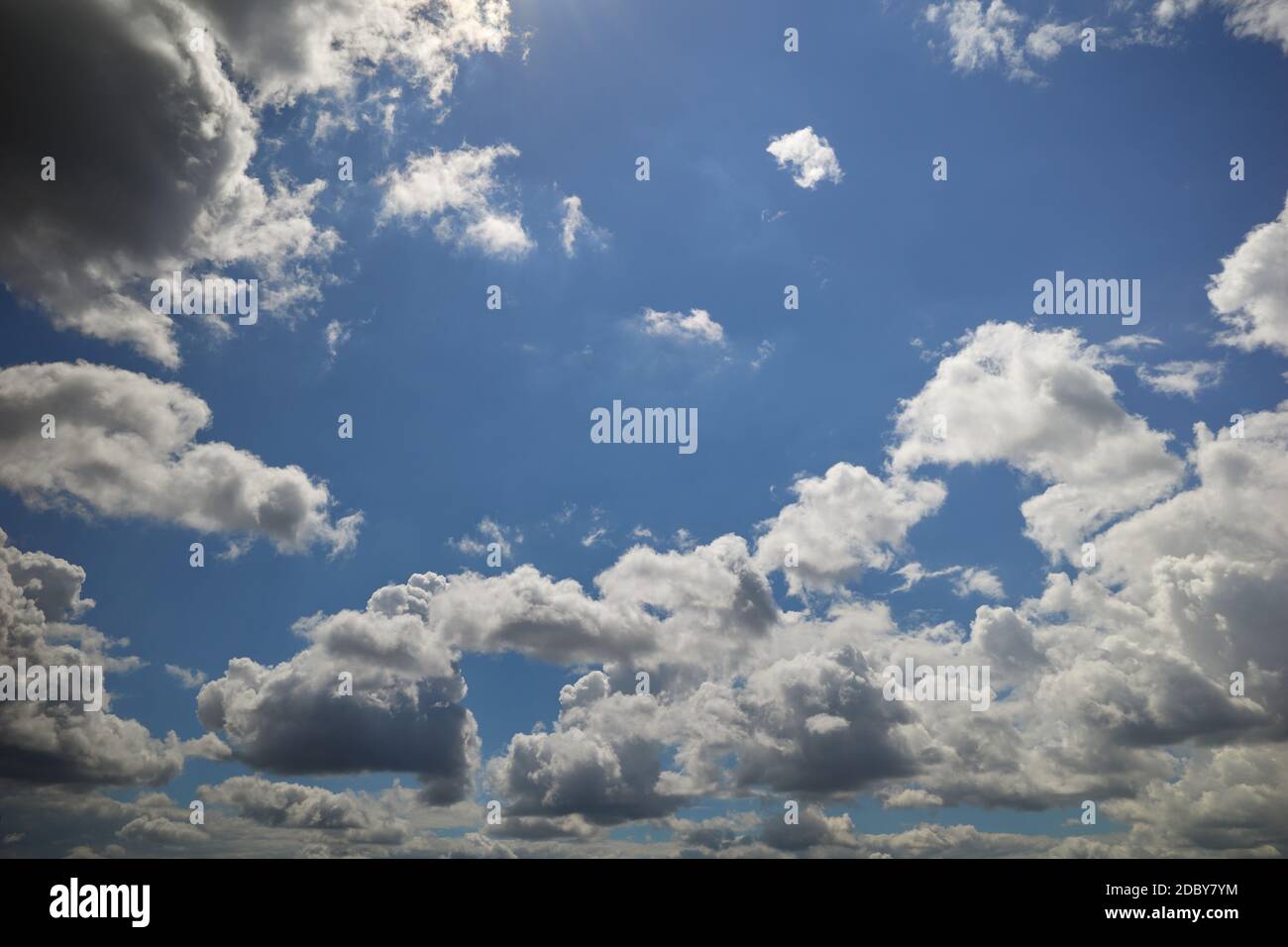Cumulus clouds in blue sky lightened by sunrays Stock Photo