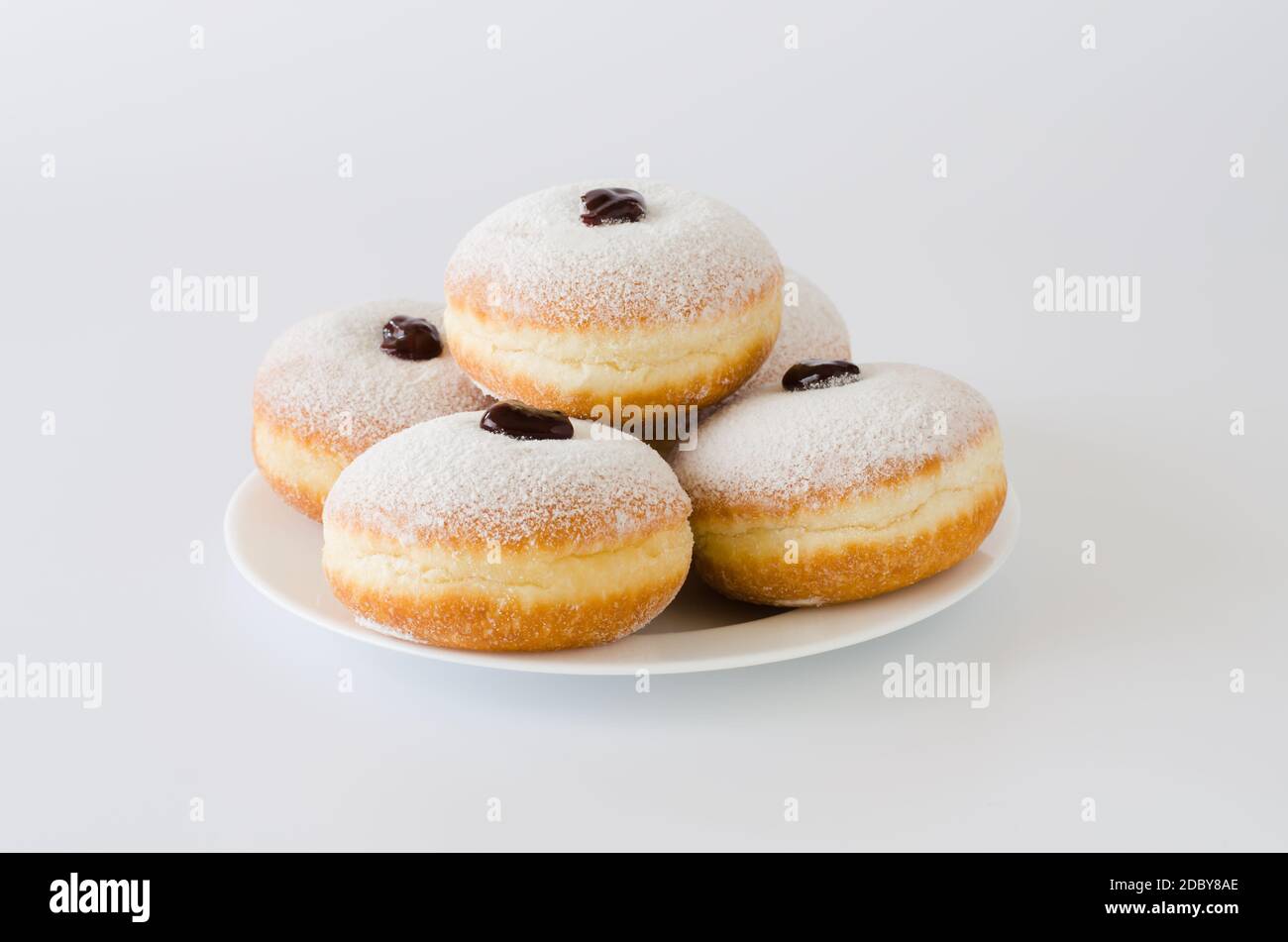 Traditional sweet donuts with powdered sugar and jam. Fat Thursday or Hanukkah celebration. Isolated on white. Stock Photo