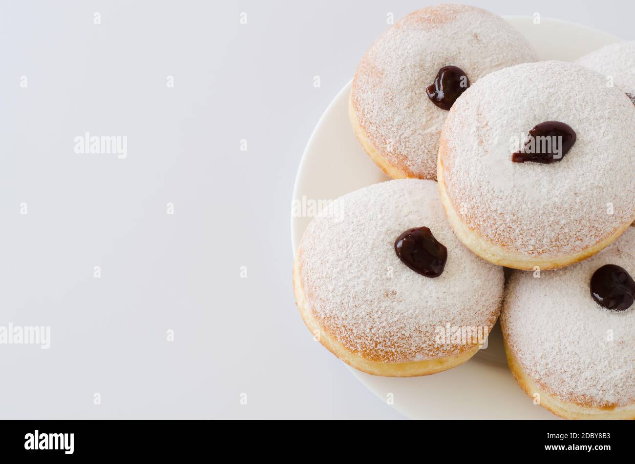 Traditional sweet donuts with powdered sugar and jam. Fat Thursday or Hanukkah celebration. Isolated on white. Stock Photo