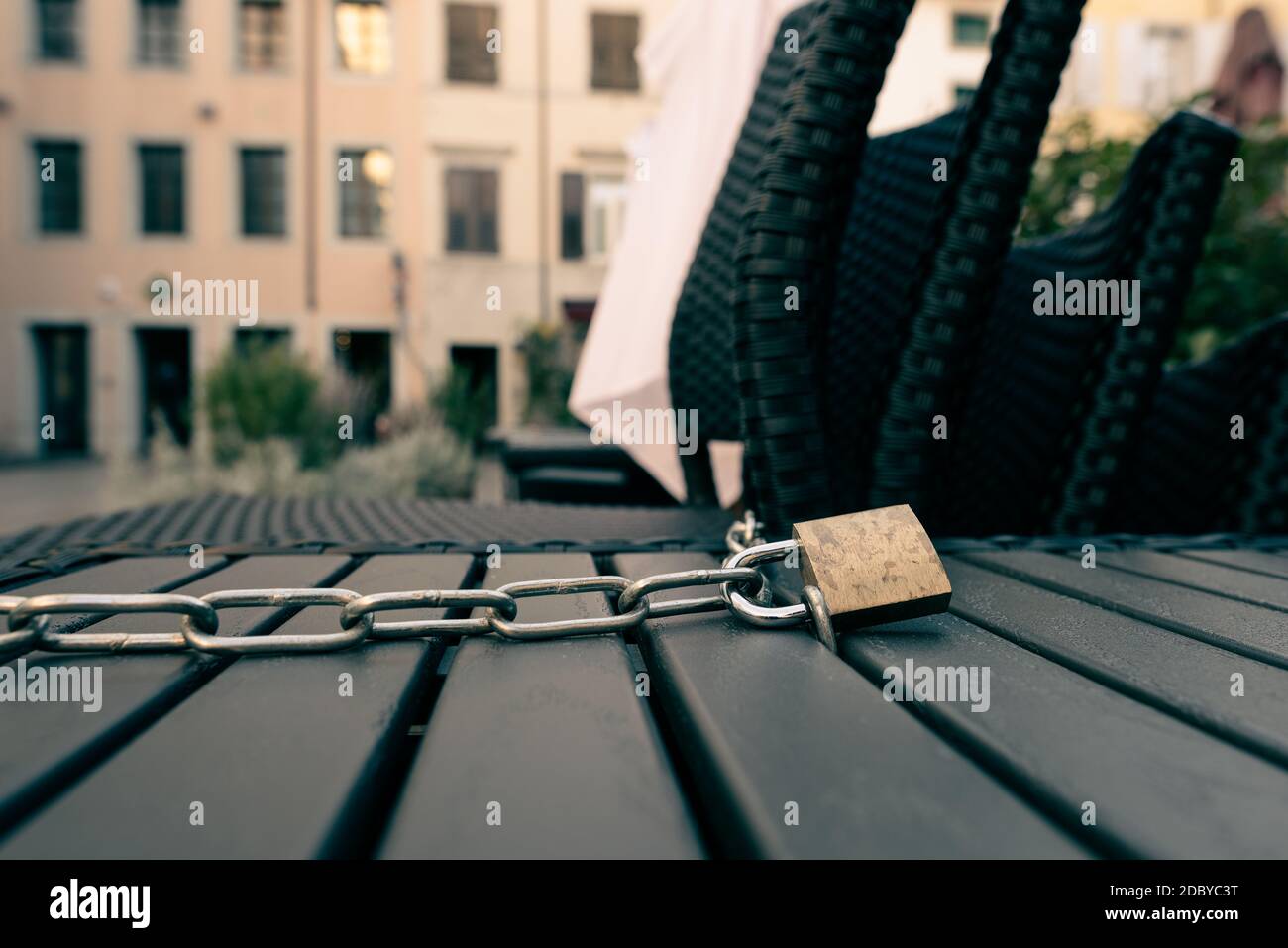 Padlock and chain locking a table and chairs of a closed open air bar during the Italian lockdown due to coronavirus. Stock Photo