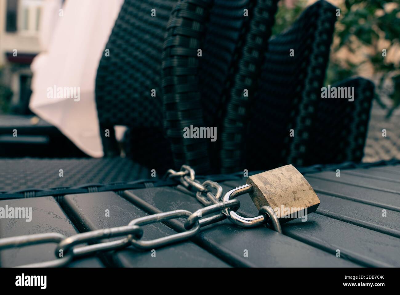 Padlock and chain locking a table and chairs of a closed open air bar during the Italian lockdown due to coronavirus. Stock Photo