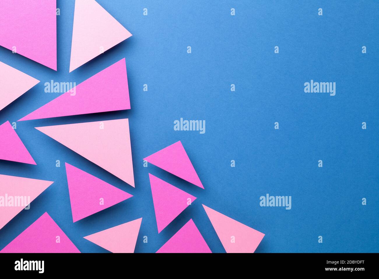 Pink triangular shapes in minimal creative style. Paper composition on blue background for presentations. Top view. Copy space Stock Photo