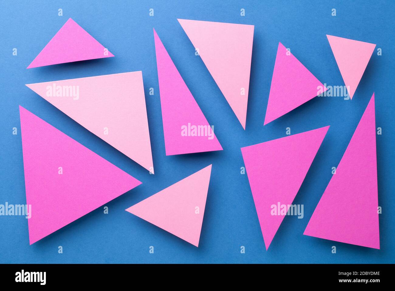 Abstract composition over blue paper background with pink triangular shapes. Minimal style. Top view Stock Photo
