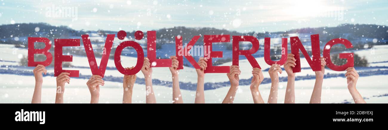 People Hands Holding Colorful German Word Bevoelkerung Means Population. Snowy Winter Background With Snowflakes Stock Photo