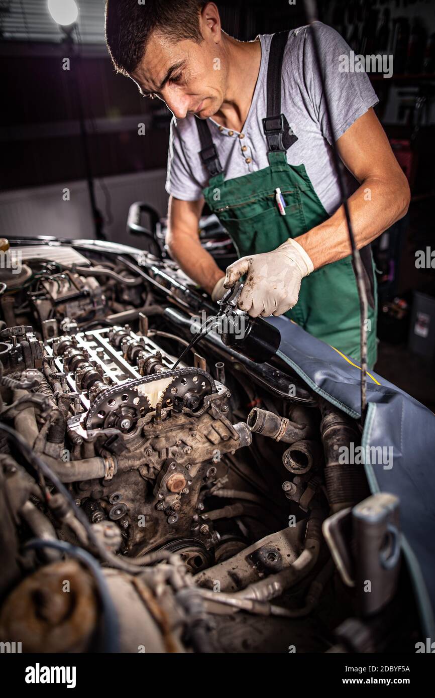 Motor oil pouring to car engine. Repair service concept Stock Photo - Alamy