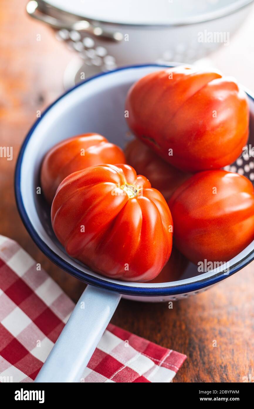 Red beefsteak tomatoes in colander. Stock Photo