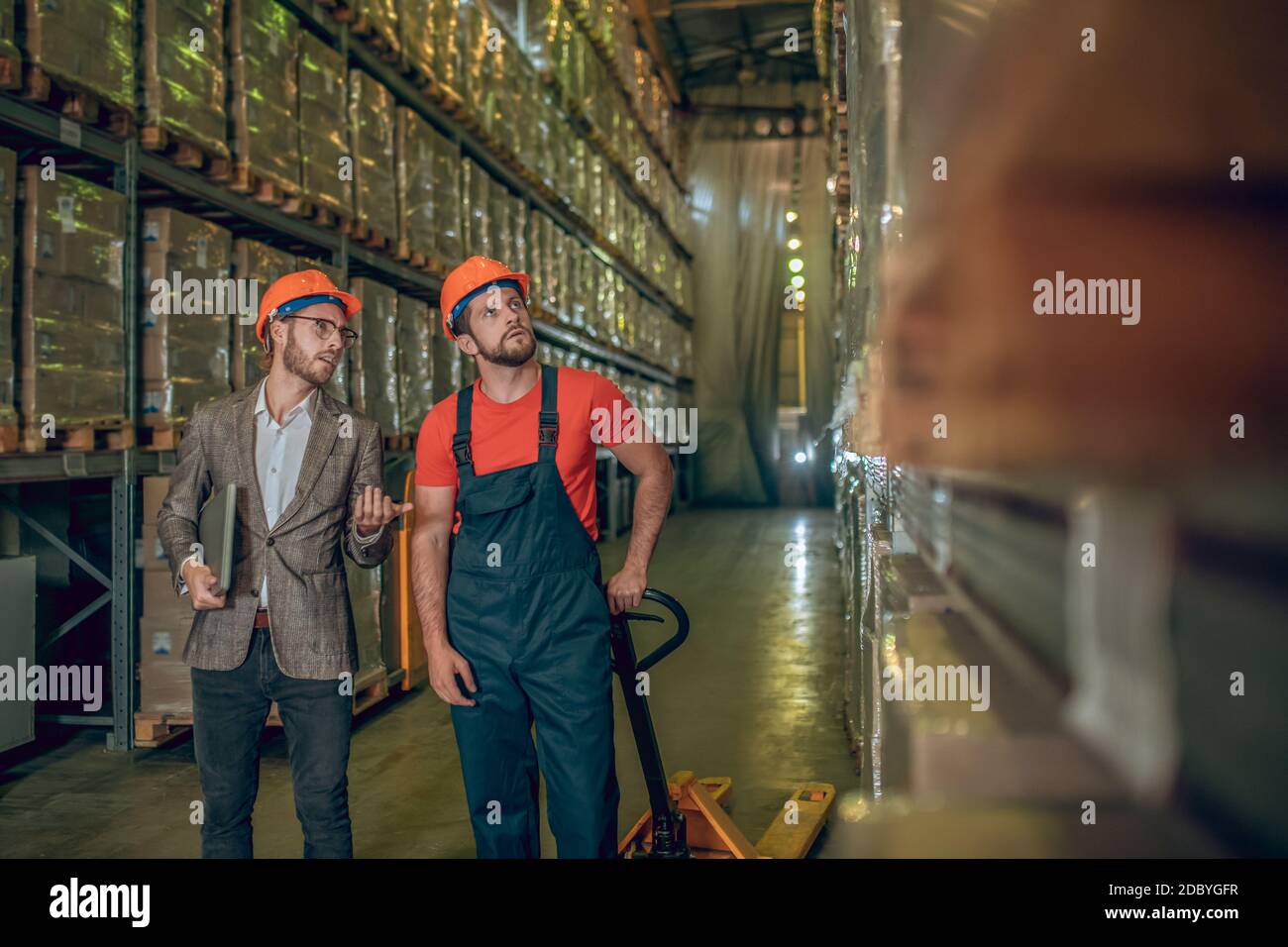 Manager inspecting warehouse while warehouse worker showing him the ...