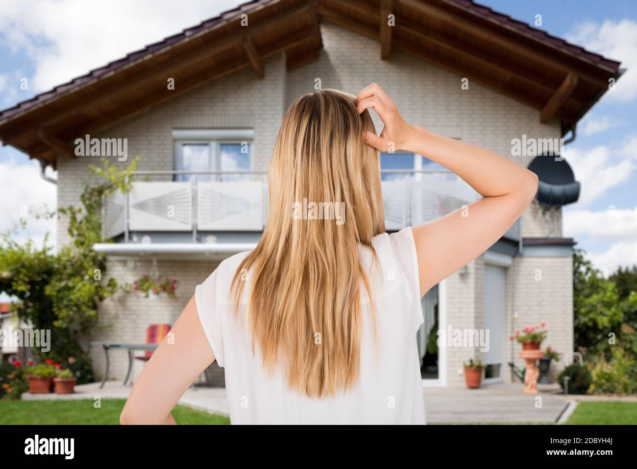 Confused Home Buyer Scratching Head In Front Of Real Estate Stock Photo