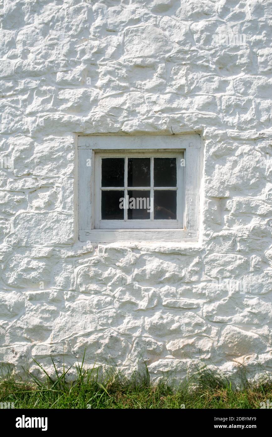 Whitewashed stone gleams in natural light with antique glass window and