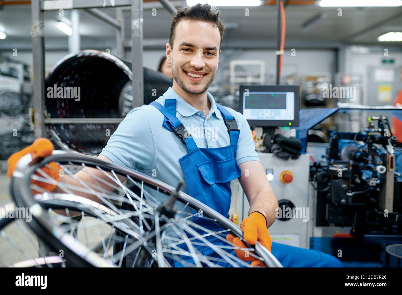 Mechanic in uniform works with bicycle wheel on factory. Bike rims and