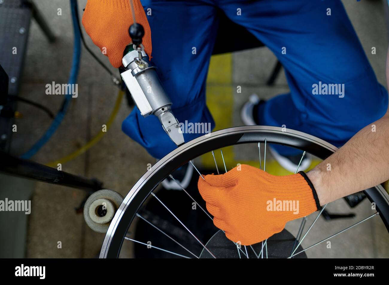 Worker with machine tool installs new bicycle rim on factory, top view. Bike wheels assembly in