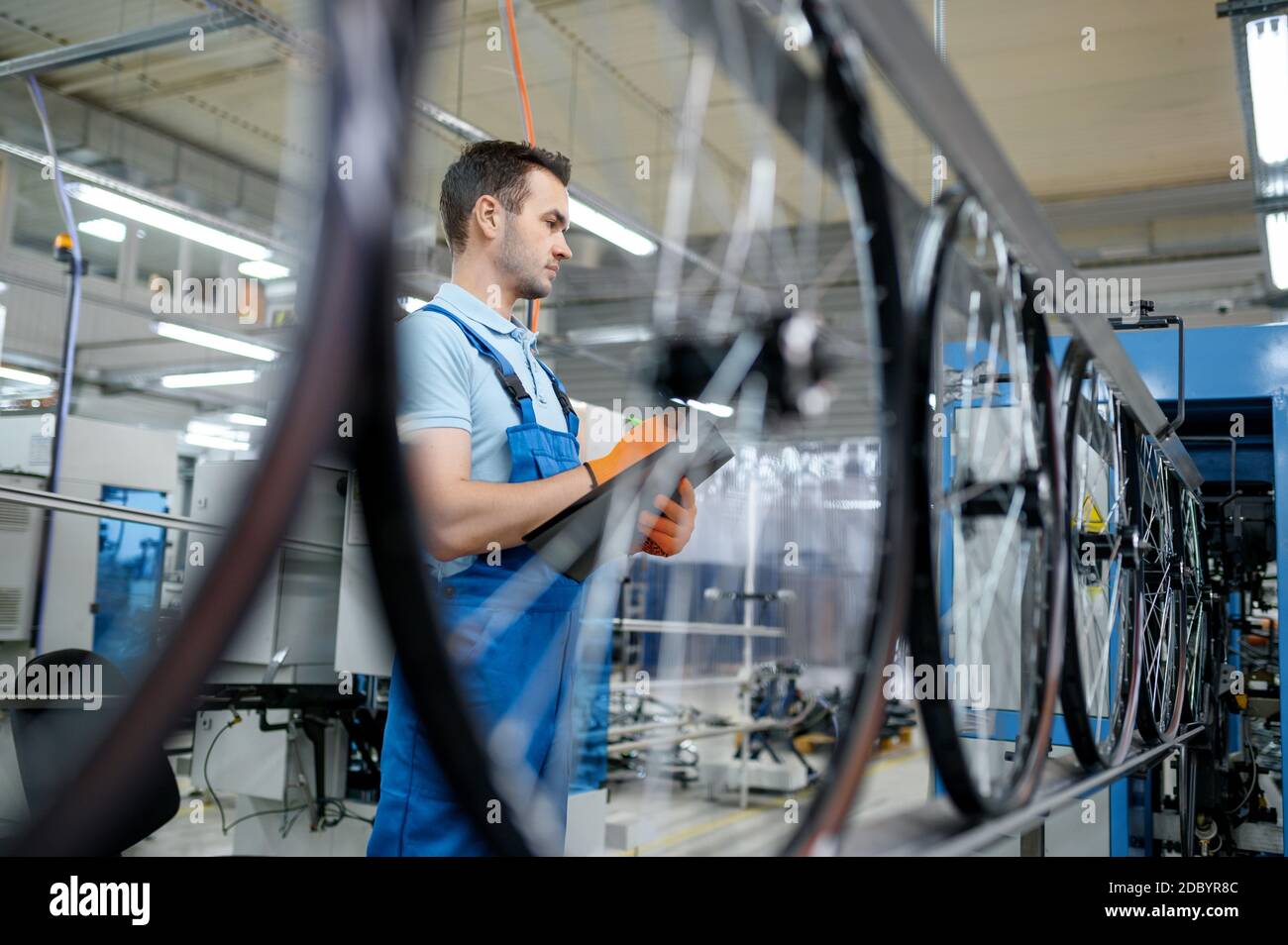 Worker at the assemly line makes bicycle wheels on factory. Bike rims
