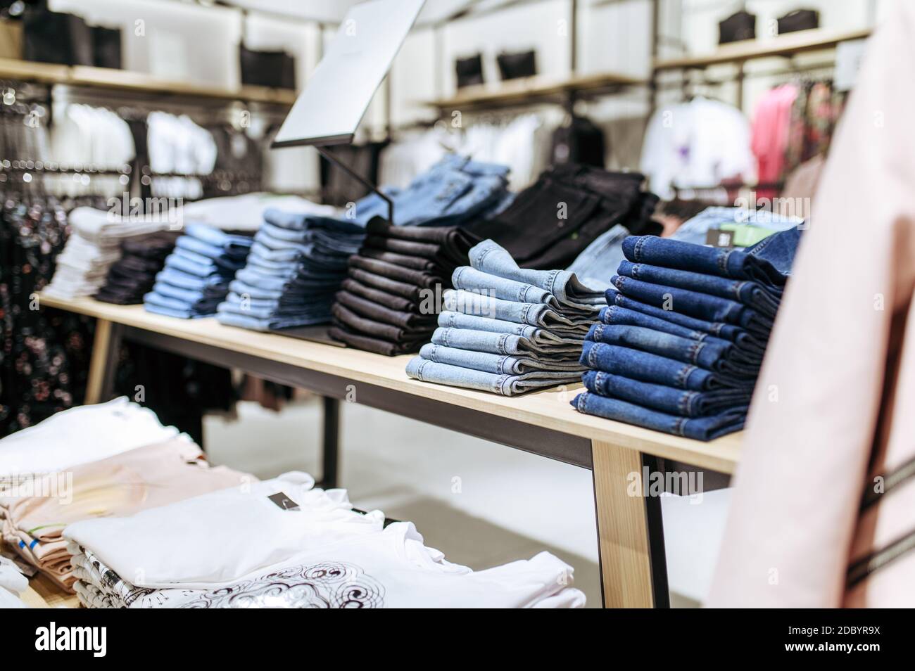 Clothes, jeans collection on shelf in clothing store, nobody. Fashion shop  or boutique interior, garment on hangers in showroom Stock Photo - Alamy