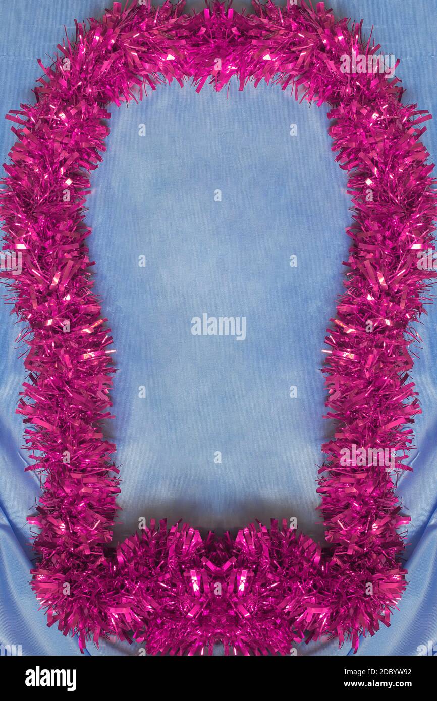 Beautiful pink frame with Christmas tinsel texture on cobalt blue silk fabric background and space to insert a text. Stock Photo