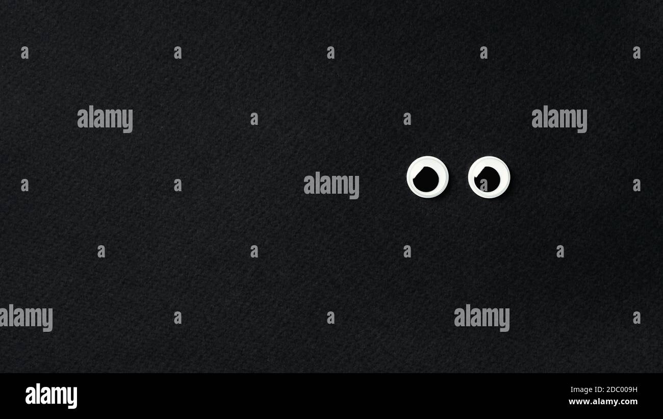 googly eyes on black background with copy space left. Top view or flat — free download