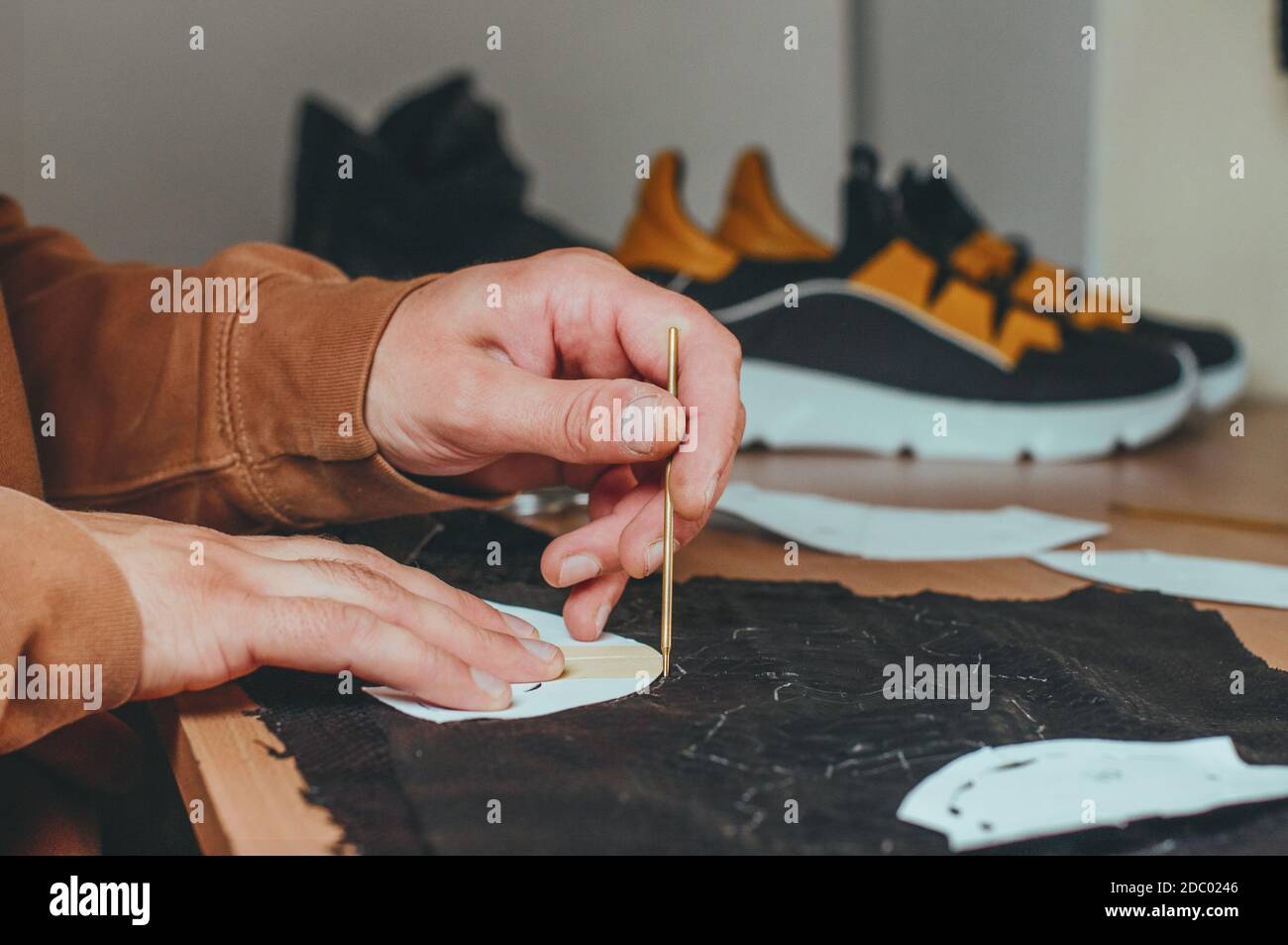 Shoemakers hands making patterns from leather in his workshop Stock Photo