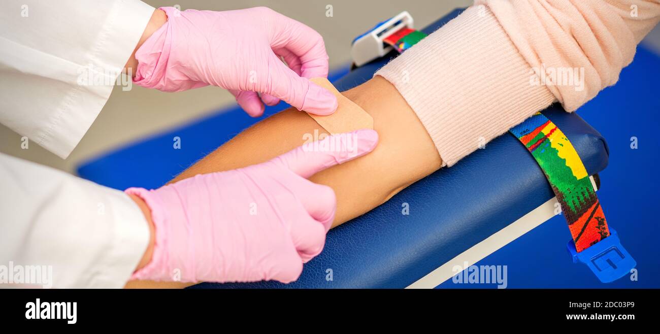 Close up of nurse hand applying adhesive plaster on arm of patient