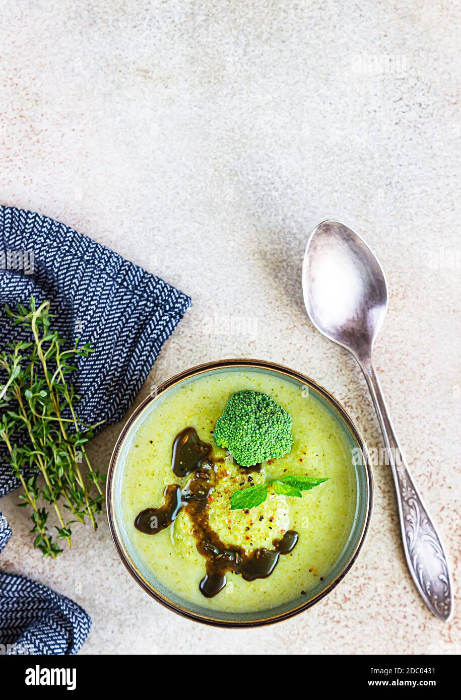 Delicious broccoli cream soup with spicy oil and mint. Vegetarian dish. Top view. Concrete background. Stock Photo