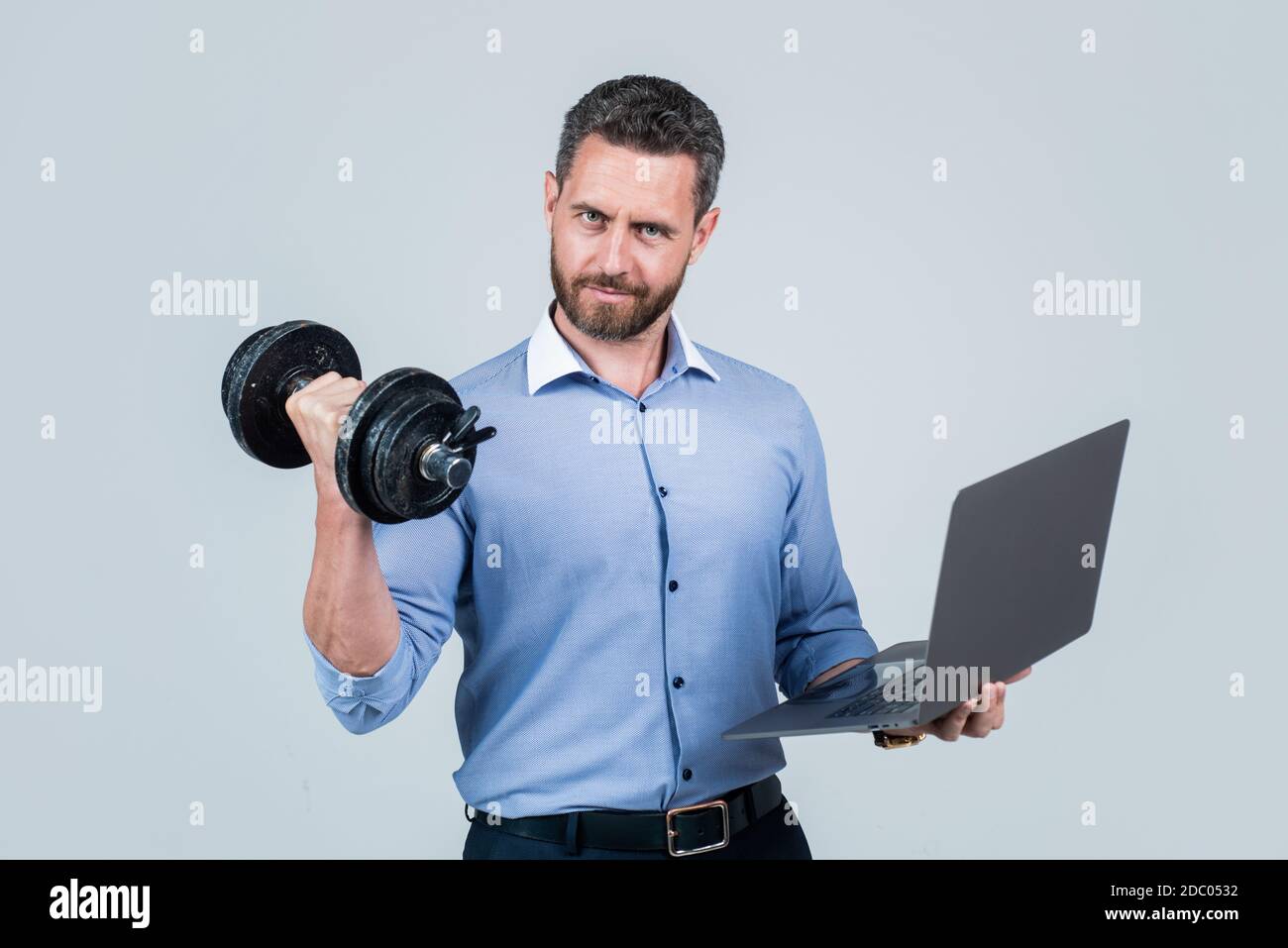Online work gym that helps spur productivity. Manager hold laptop curling dumbbell. Strength training. Business coach. Fitness at work. Weightlifting workout