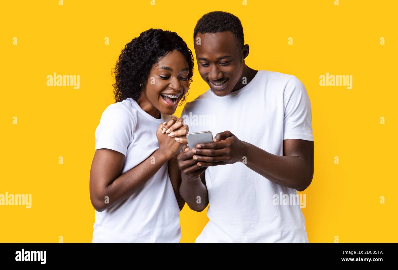 Excited black couple looking at mobile phone screen Stock Photo