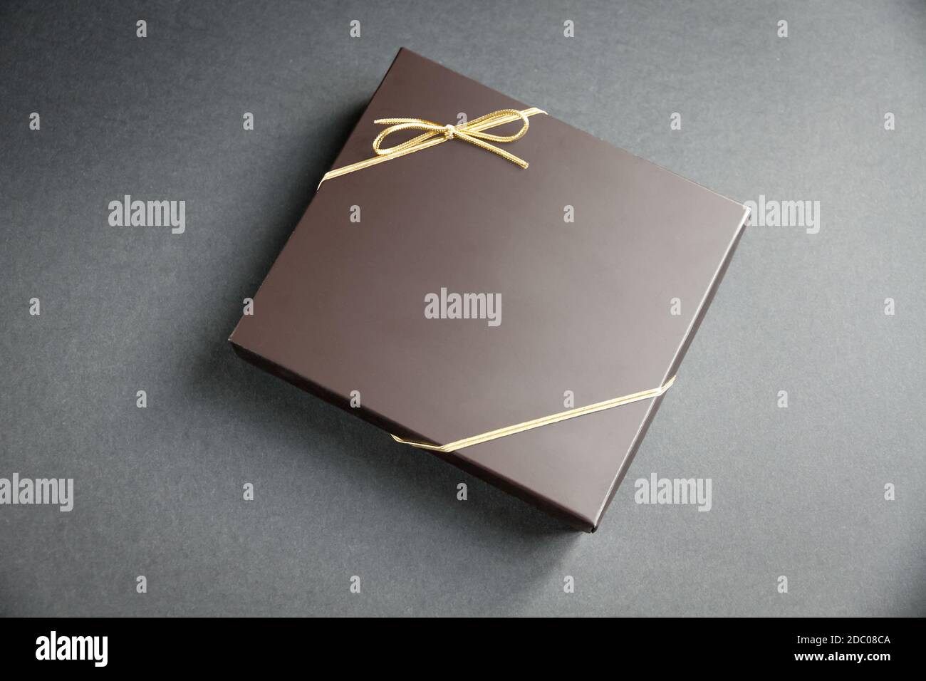 Black luxury gift box with a golden ribbon on black background Stock
