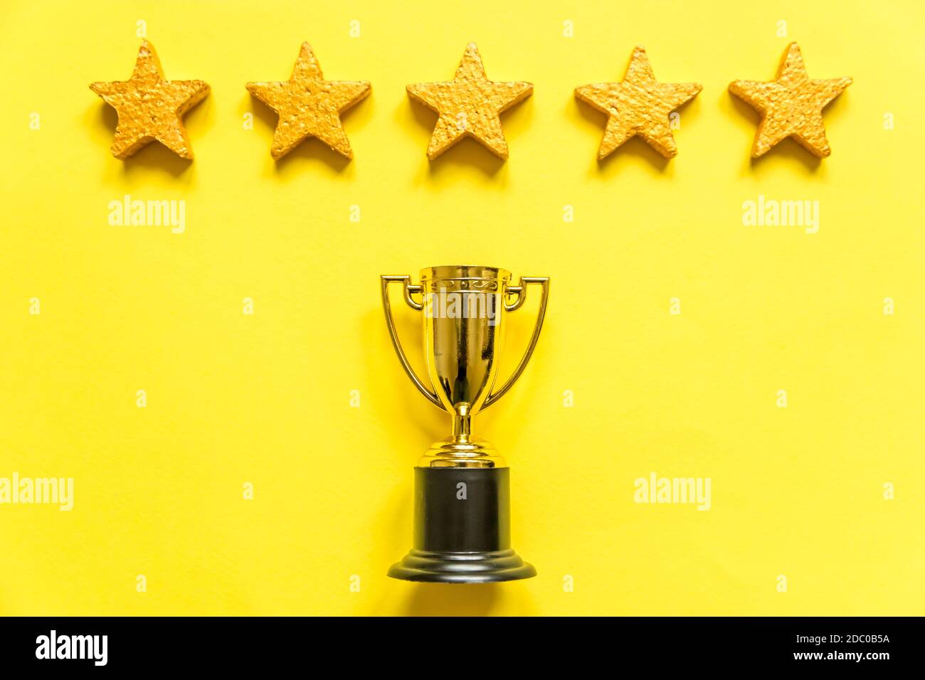https://c8.alamy.com/comp/2DC0B5A/simply-flat-lay-design-winner-or-champion-gold-trophy-cup-and-5-stars-rating-isolated-on-yellow-background-victory-first-place-of-competition-winnin-2DC0B5A.jpg