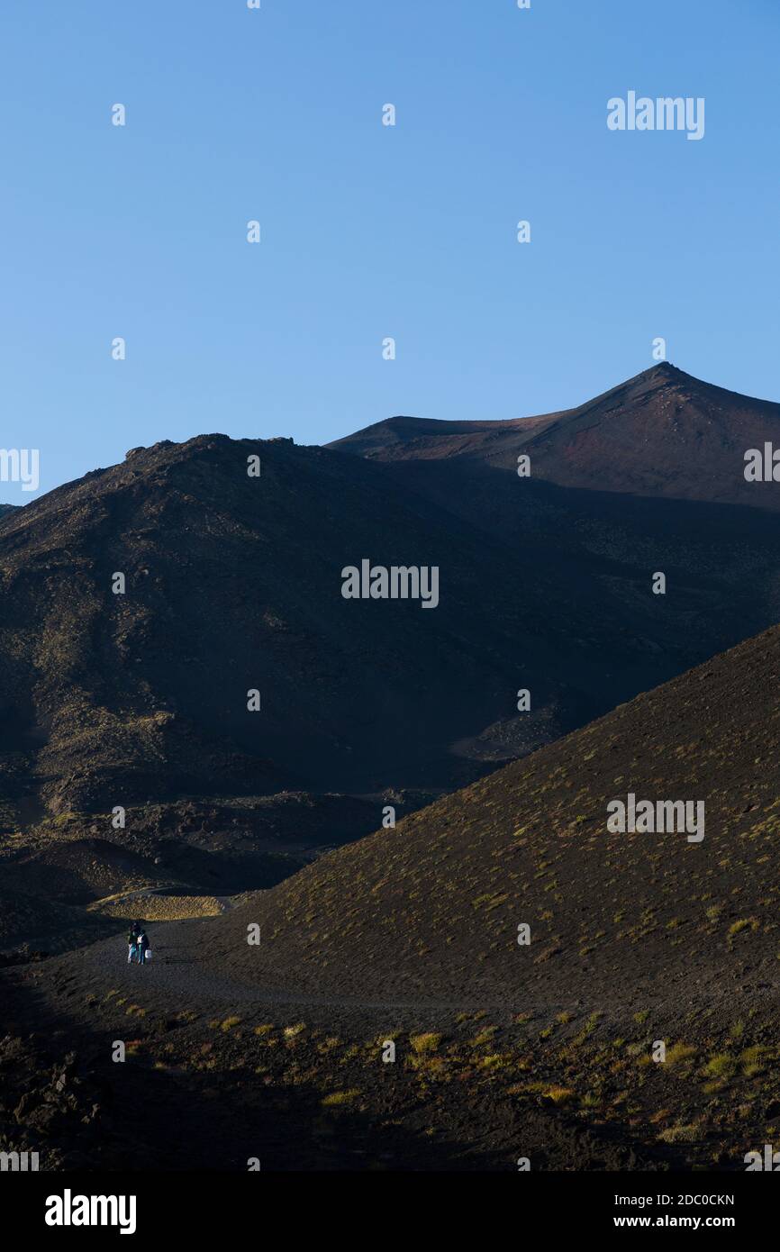 Sicily, Italy. Tourists make the steep climb up the Silvestri Superiori crater near the summit of Mt Etna. Stock Photo