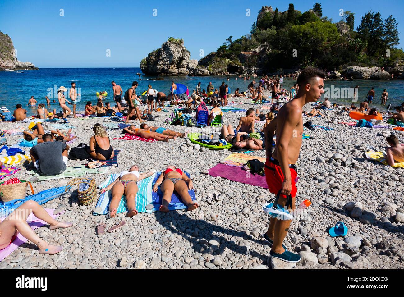 Sicily, Italy. Tourists crowd the Spiaggia Isola Bella beach on a warm sunny day. Stock Photo