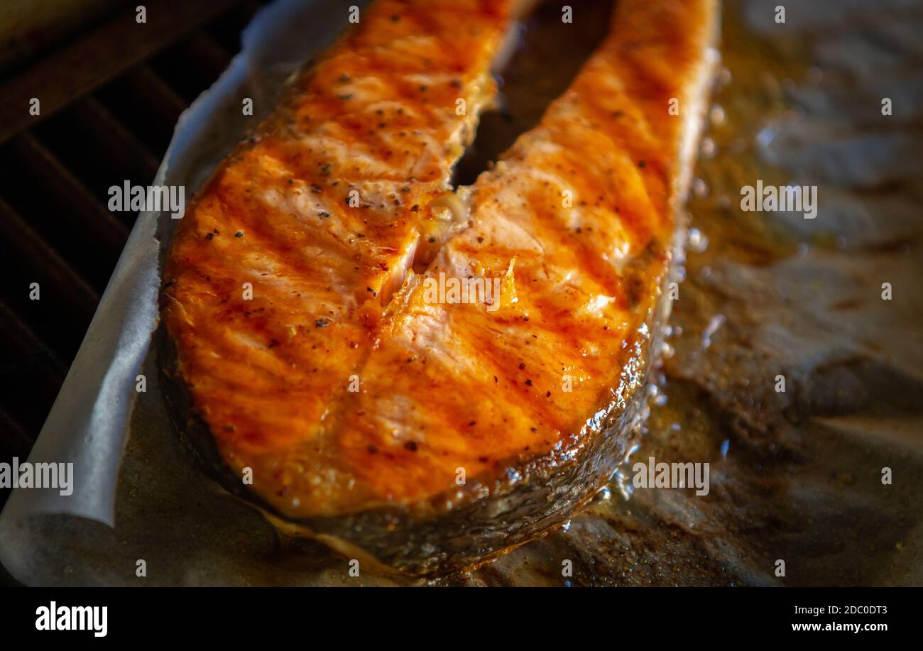 Salmon fish steak cooking on parchment paper in seafood restaurant