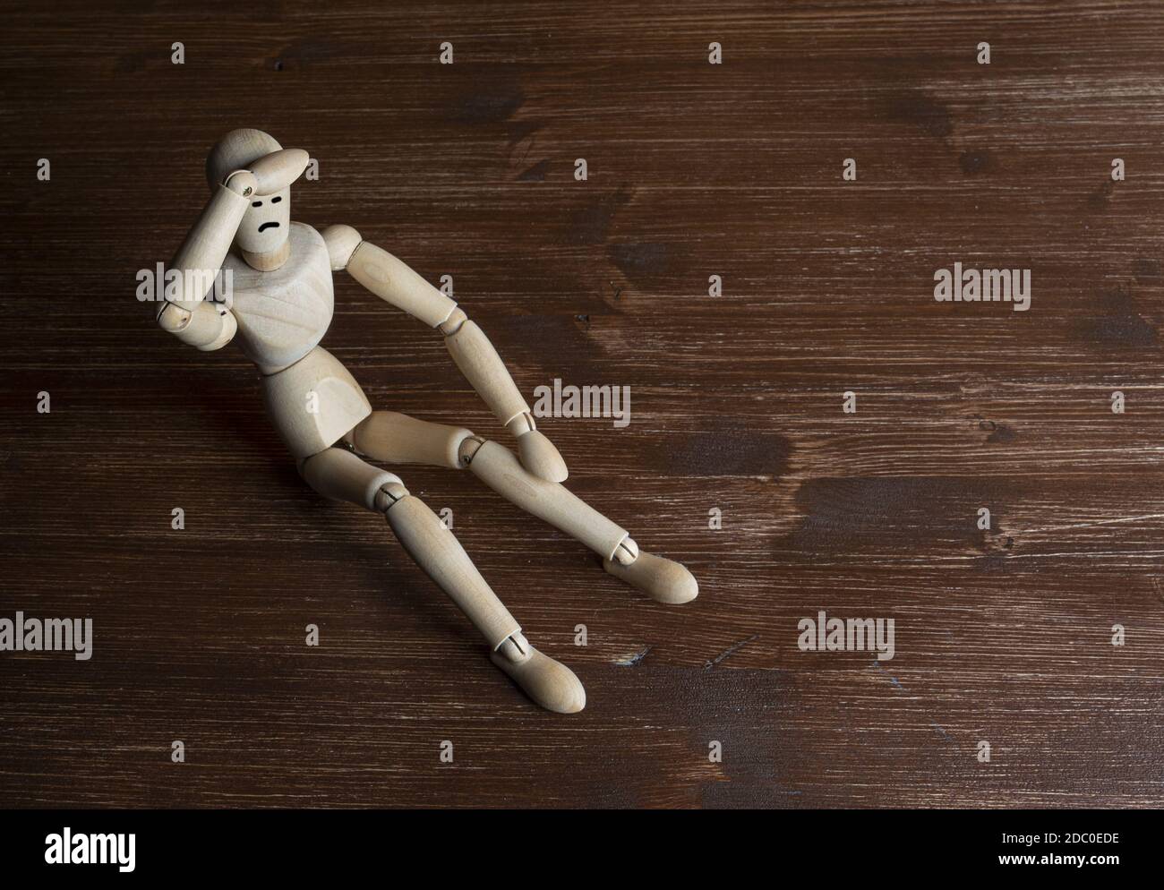 a wooden mannequin with his hands on his head in despair Stock Photo