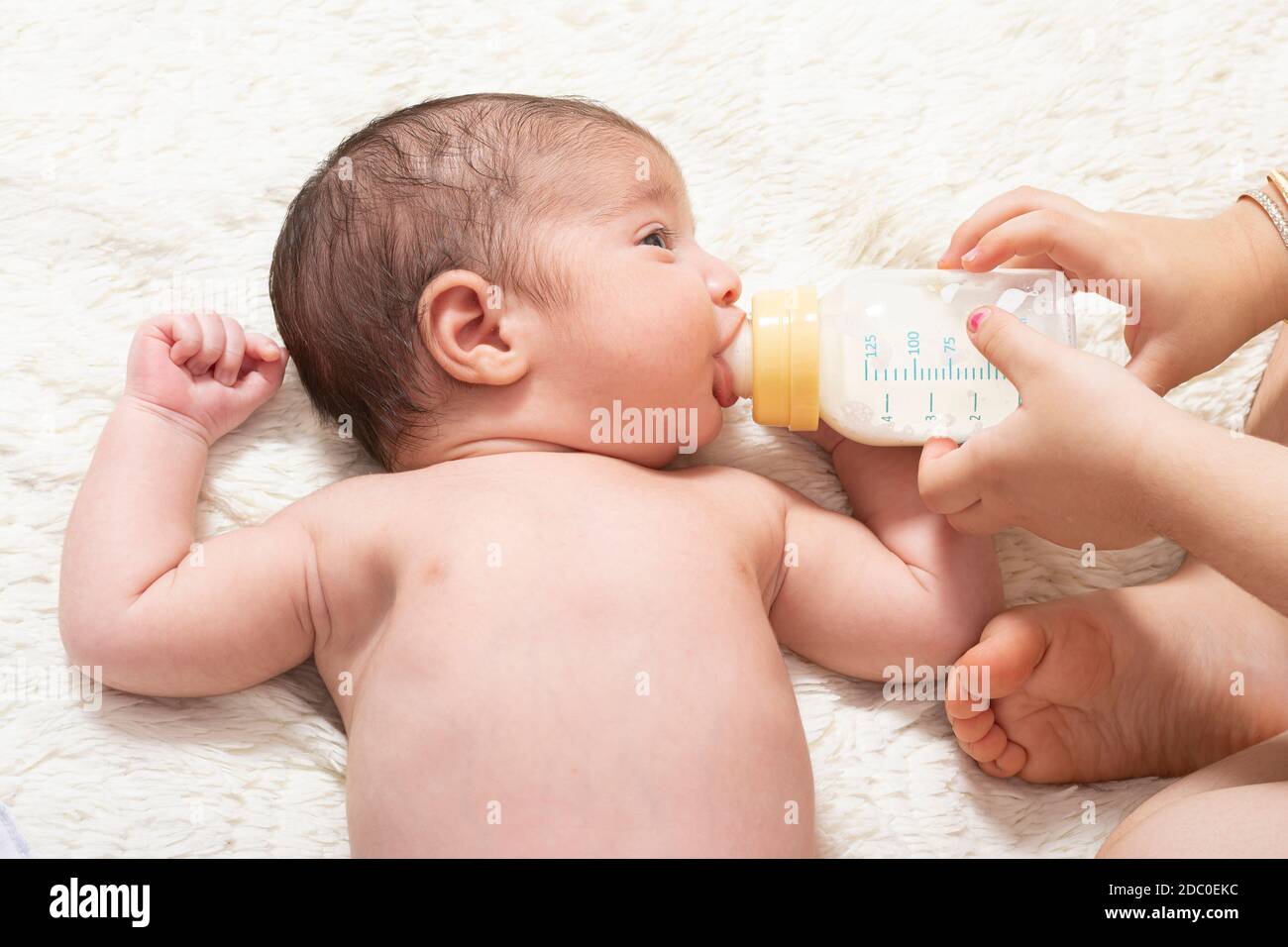 https://c8.alamy.com/comp/2DC0EKC/young-sister-feeding-little-newborn-brother-by-milk-bottle-on-bed-2DC0EKC.jpg
