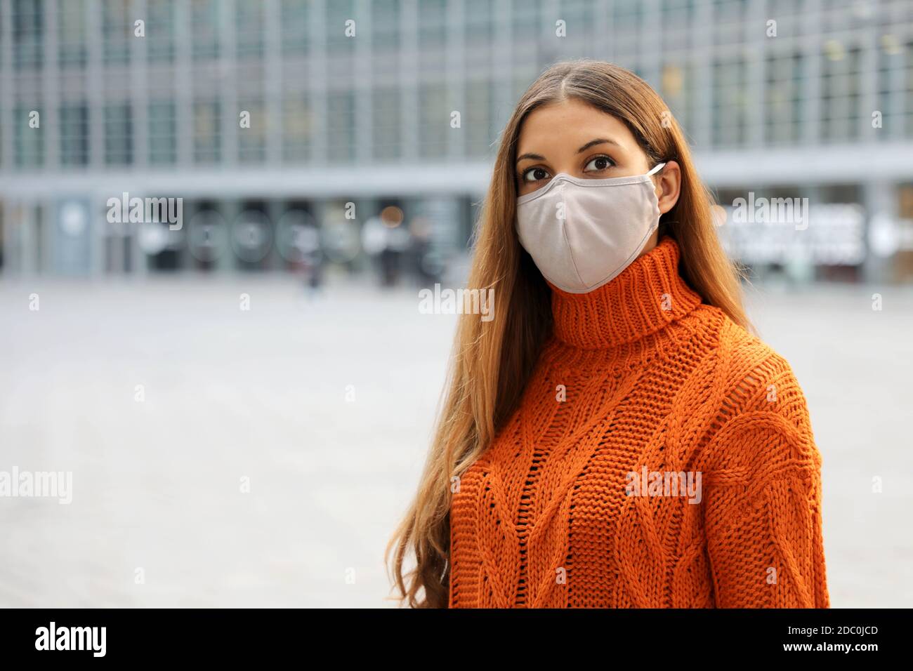 Portrait of a young business woman wearing protective mask  standing on the street looking in front of her worried. Copy space. Stock Photo