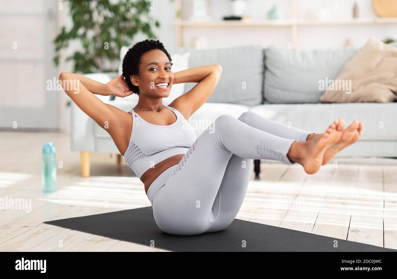 Young black woman with trained body doing abs exercise on yoga mat indoors  Stock Photo - Alamy