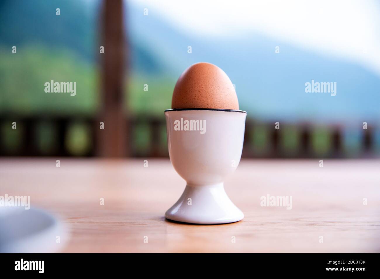 boiled egg in eggcup on wooden table outside, breakfast eggin white egg cup close-up Stock Photo