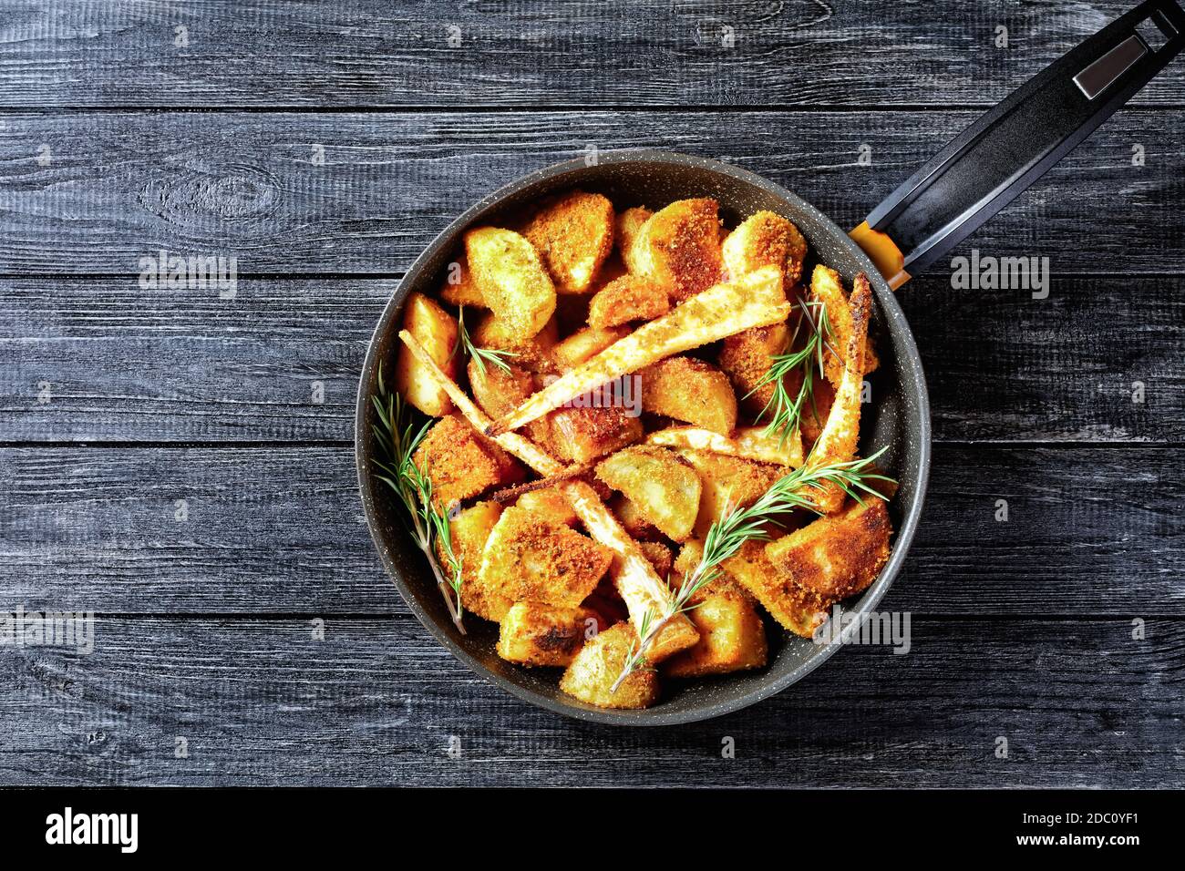 Oven baked root vegetables: parsnip and potato wedges breaded in  breadcrumbs with smoked paprika and fresh rosemary sprigs served on a  wooden backgrou Stock Photo - Alamy